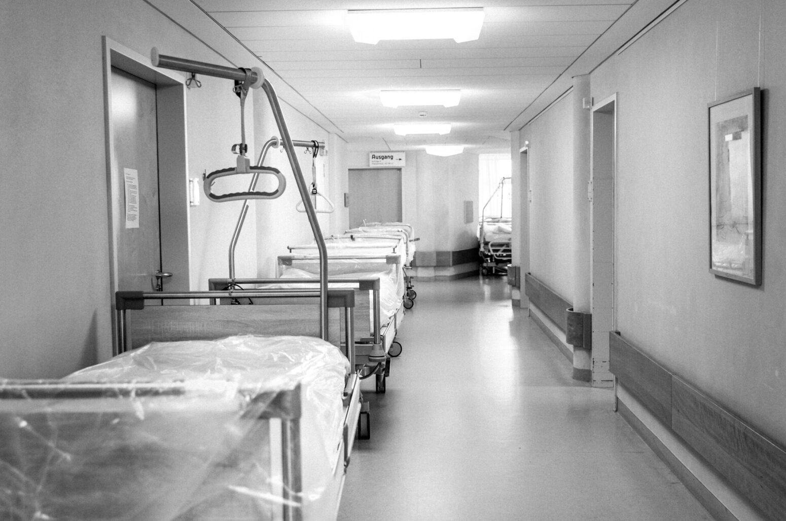 A black-and-white photo of the empty hallway of a hospital.