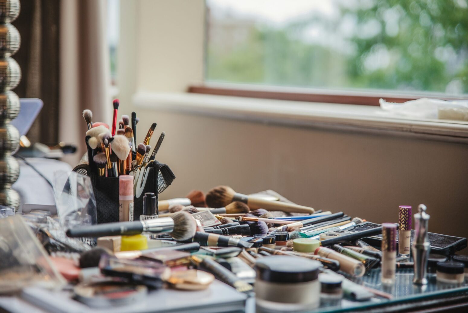A desk absolutely covered in different makeup and applicators.