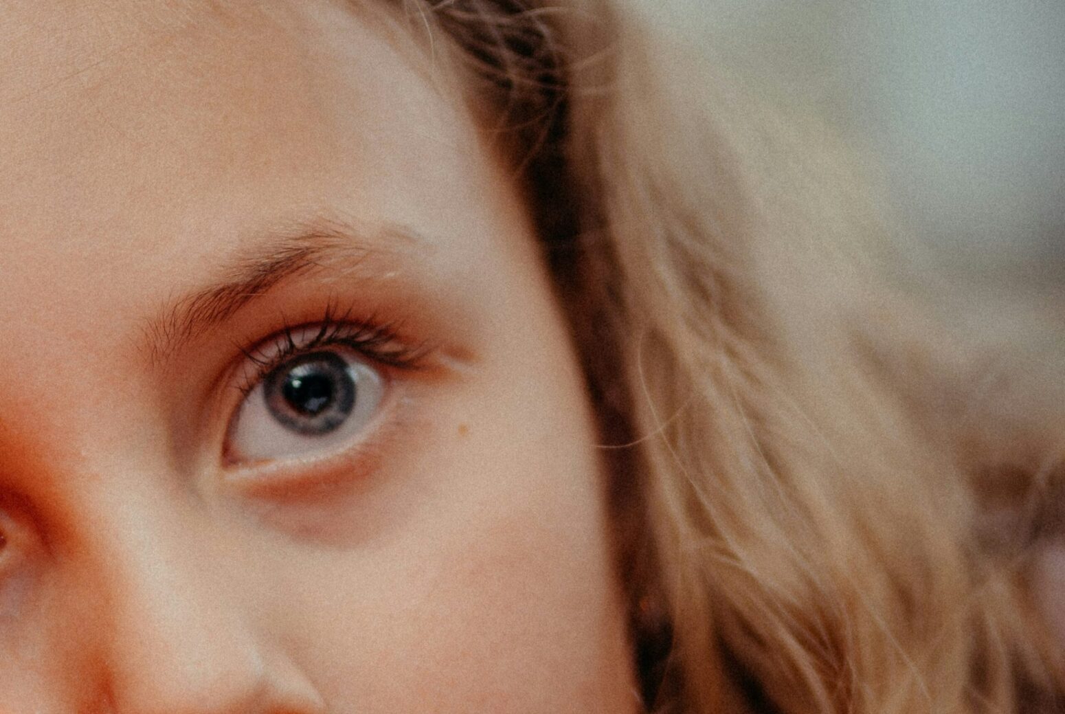 A close-up of half of a little girl's face. She has blue eyes and blonde hair.