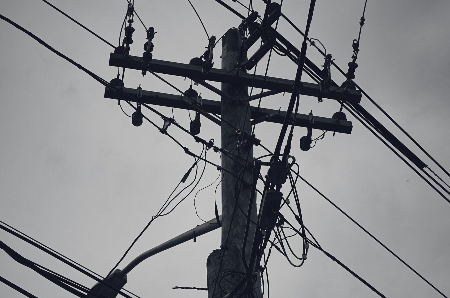 A black-and-white photo of a utility pole and power lines.
