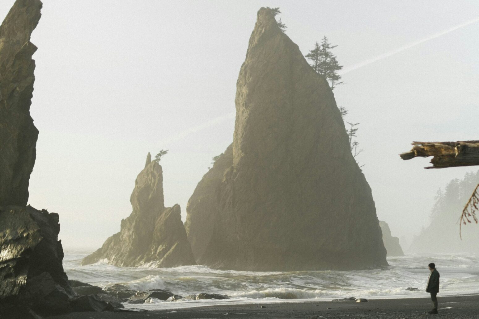 A man standing on the shore of an island surrounded by large rocks