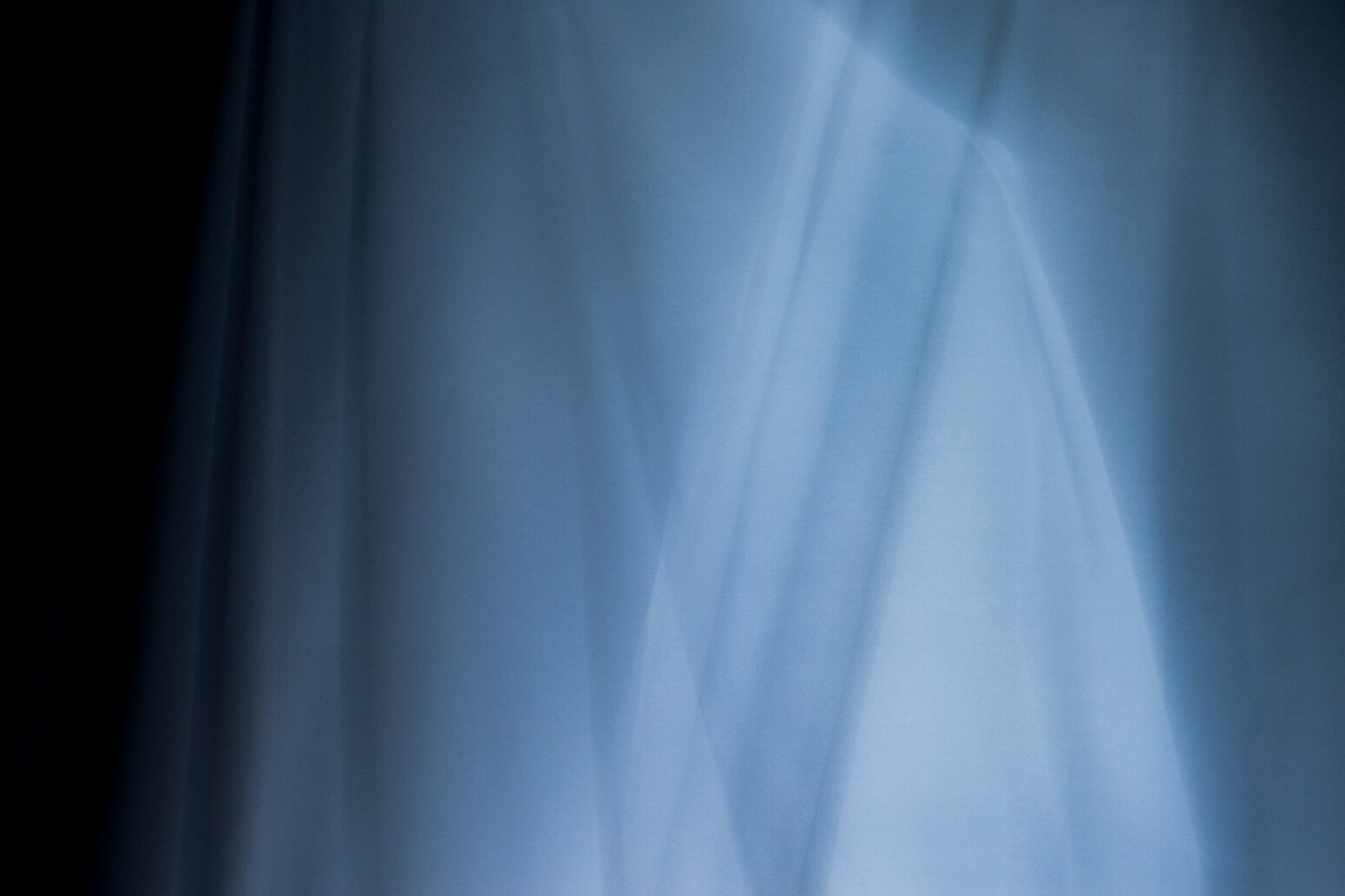 Glowing, blue sheets that looks like ghosts against a black background