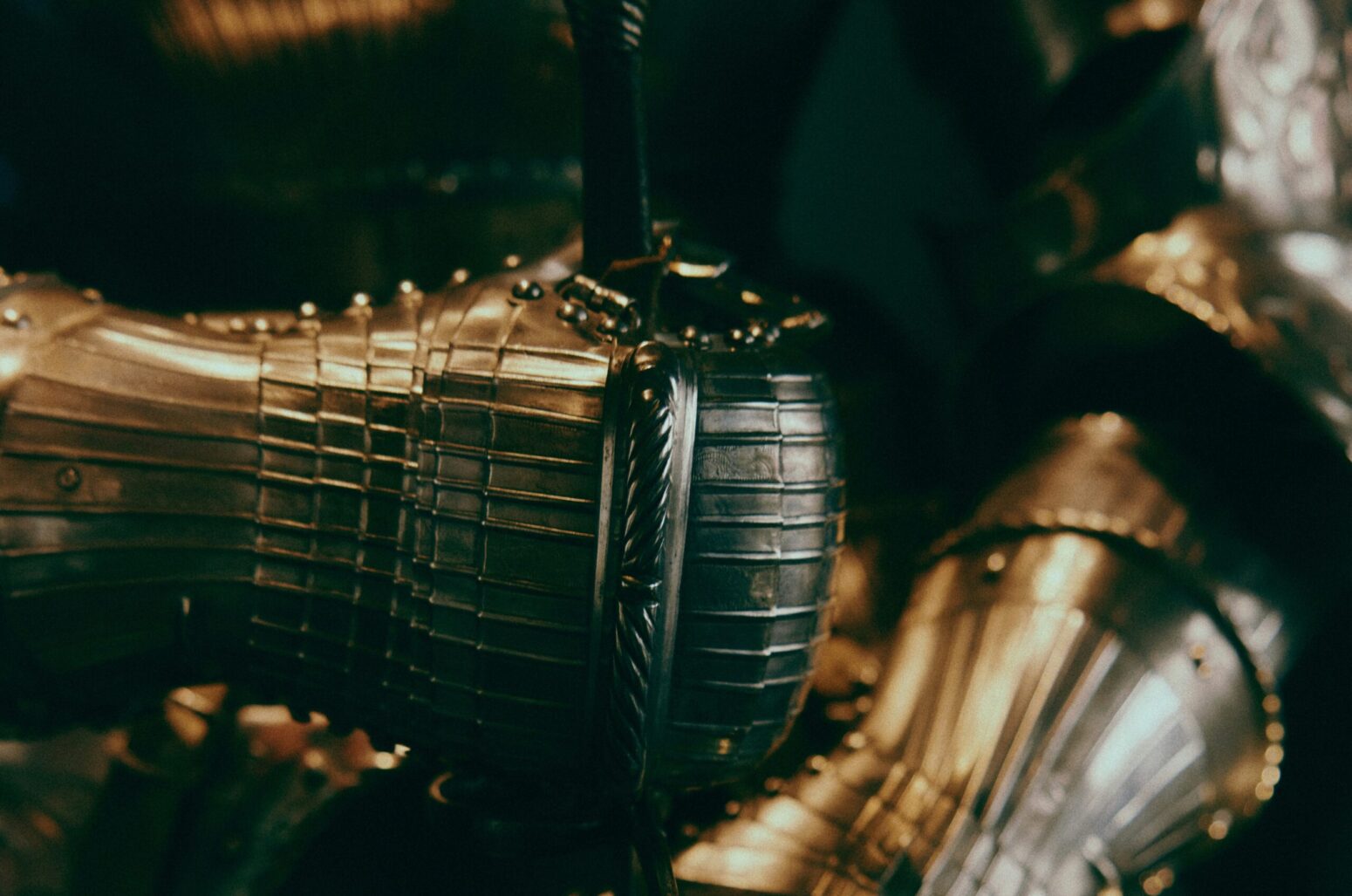 A close-up of a gauntlet on a suit of armor holding the hilt of a sword