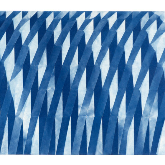 A folded cyanotype photograph with a repeated pattern of vertically stretched diamonds.