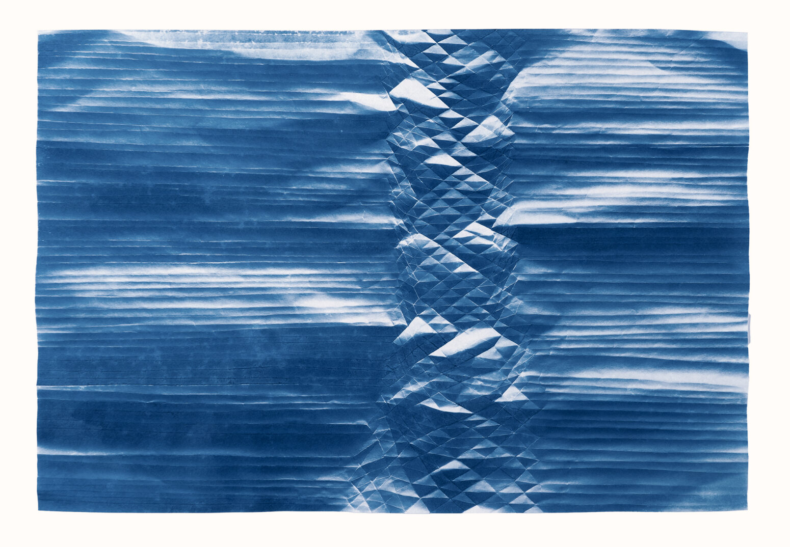 A folded cyanotype showing a spine of diamonds like a mountain range surrounded on both side by horizontal lines.