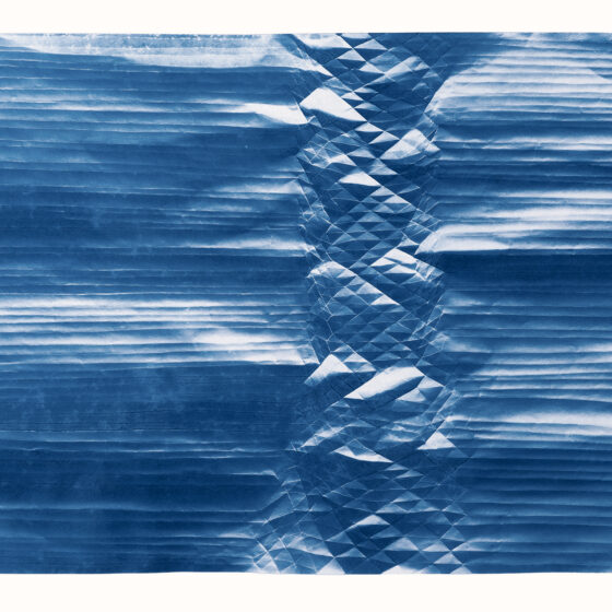 A folded cyanotype showing a spine of diamonds like a mountain range surrounded on both side by horizontal lines.