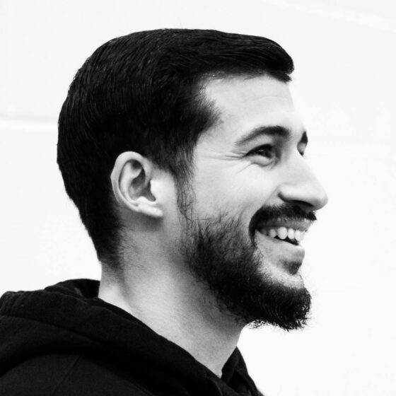 Black and white photo of a Cuban man with dark, short hair and a beard, looking to the right and smiling