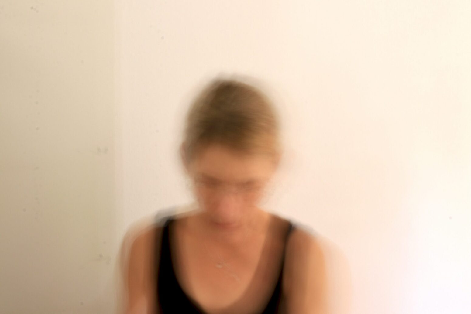 This blurry photograph shows a woman in a black tanktop.
