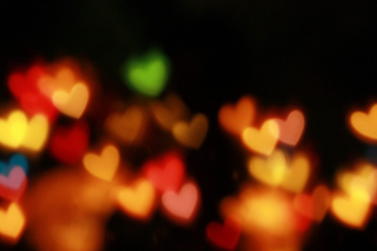 This photograph shows a blurred perspective of many hearts that are green, red, yellow, and orange.