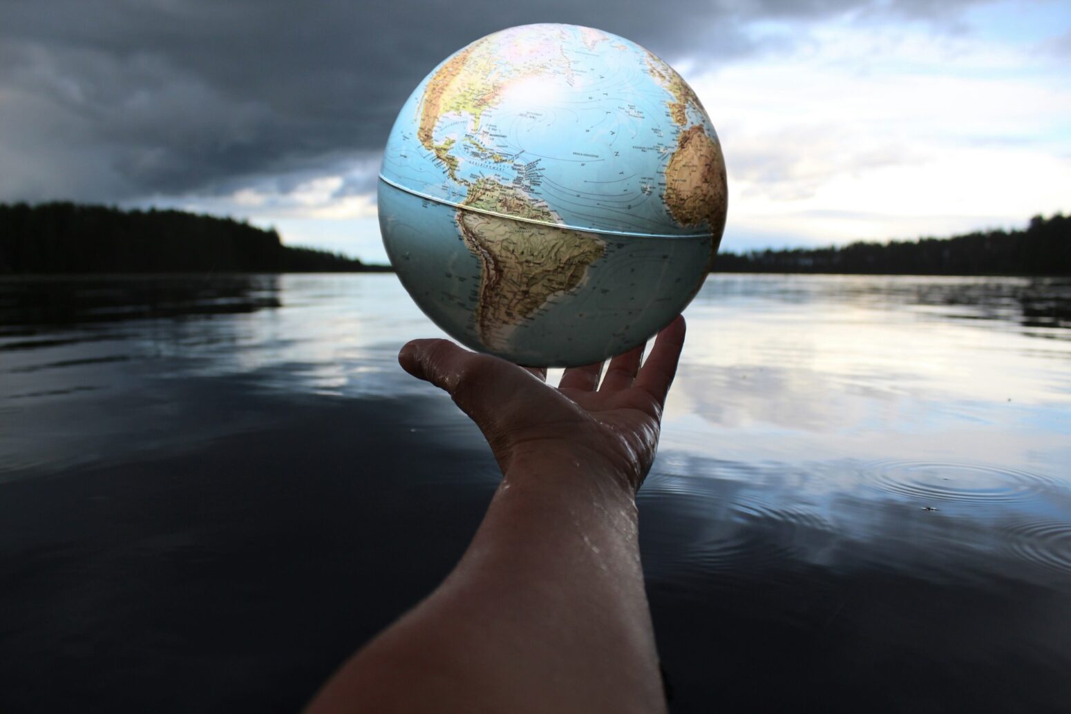 This photograph shows a geographic sphere of the earth, with a lake being in the background.