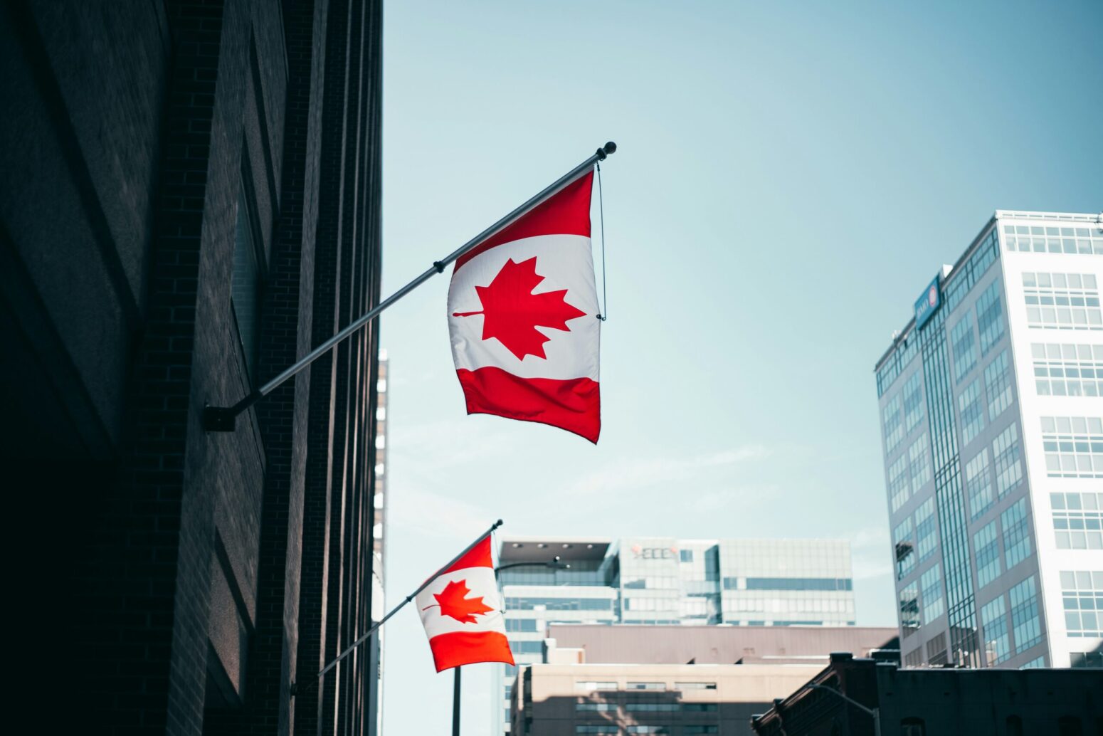 This photograph shows a picture of the city with two Canadian flags hung on the building to the left.