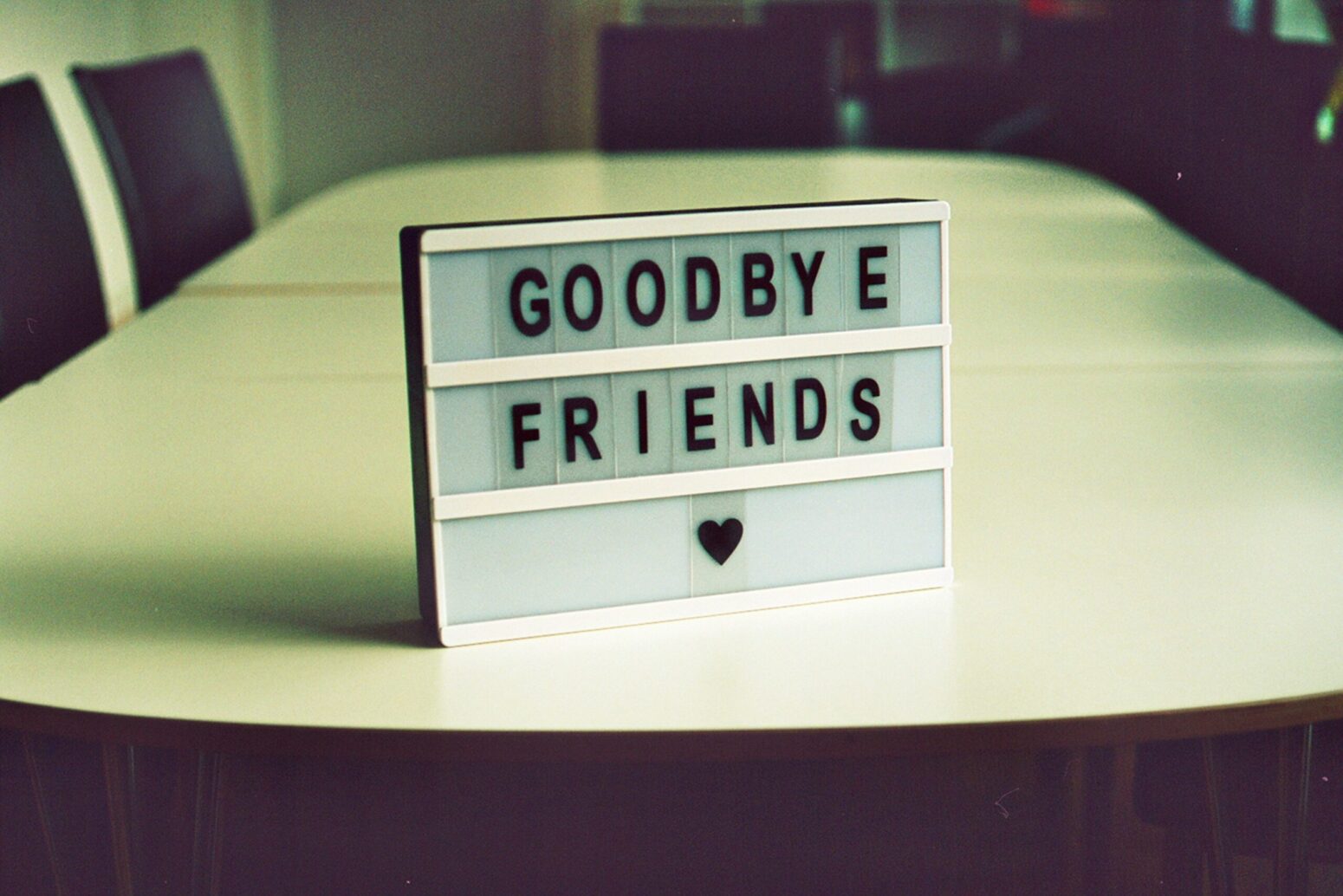 A message made out of individual letters slide into rows: "Goodbye Friends" heart shape. The item they're on sits on a table in a dark room