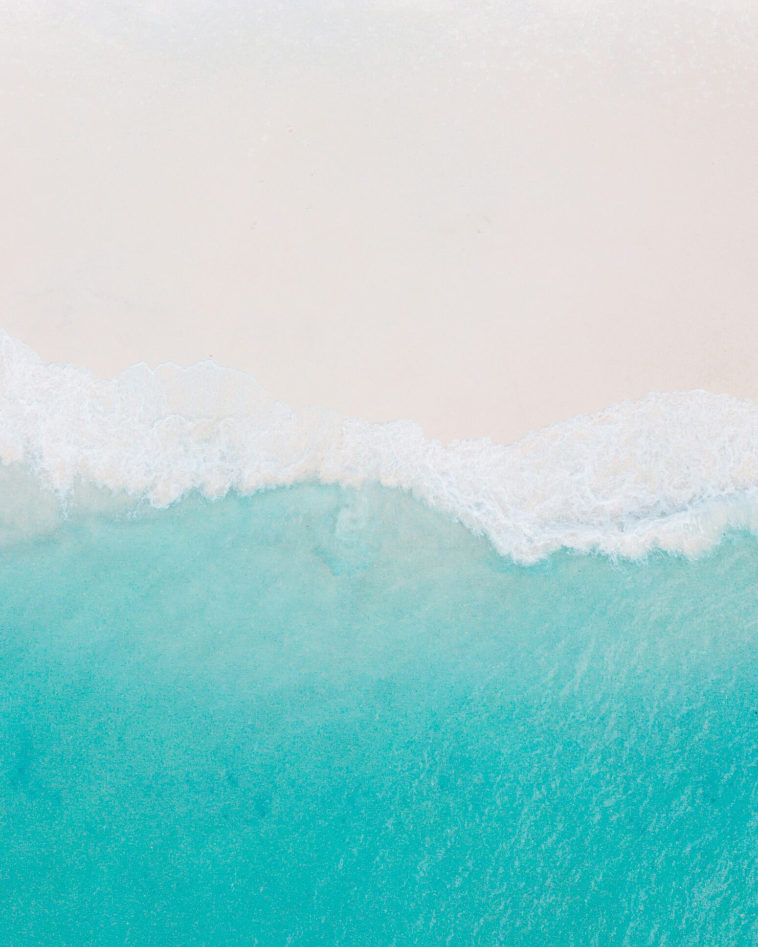 Cyan blue water crashing against white sand