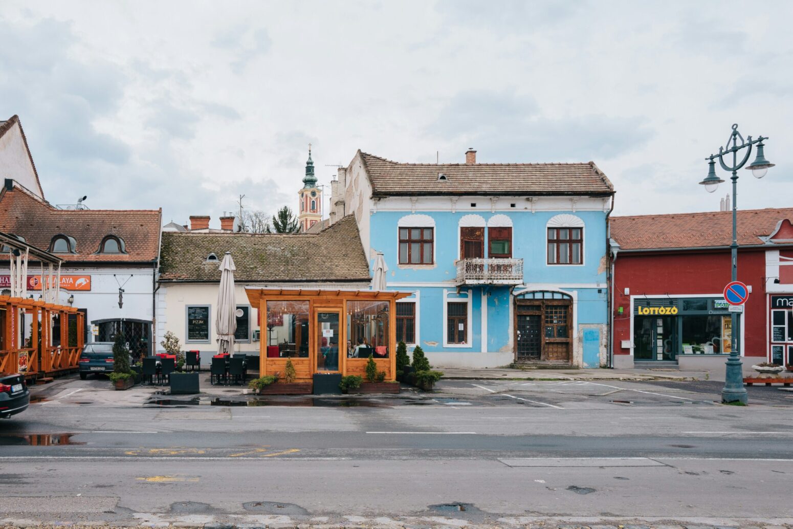 This photograph shows a small town with orange, blue, red, and multiple other buildings surrounding the street.