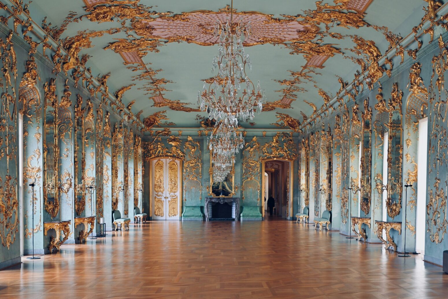 An opulent blue-and-gold ballroom with chandeliers and floor-to-ceiling windows.
