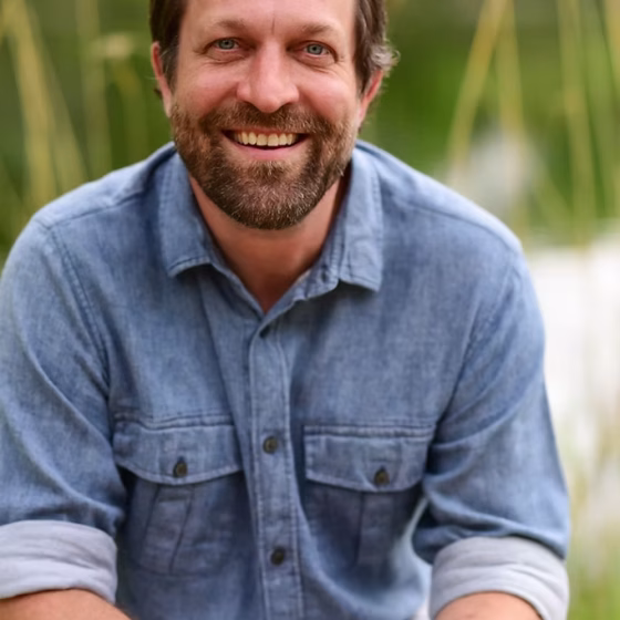 Man in a blue button up smiling at the camera