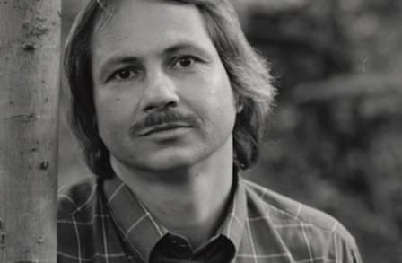 A blakc and white picture of a man with medium length hair and a mustache