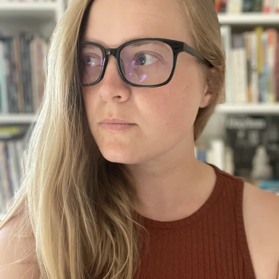 A blond woman with black glasses looking sideways