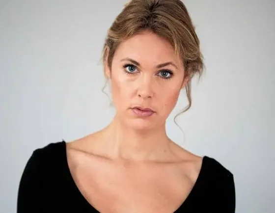 Blond woman standing against a white backdrop
