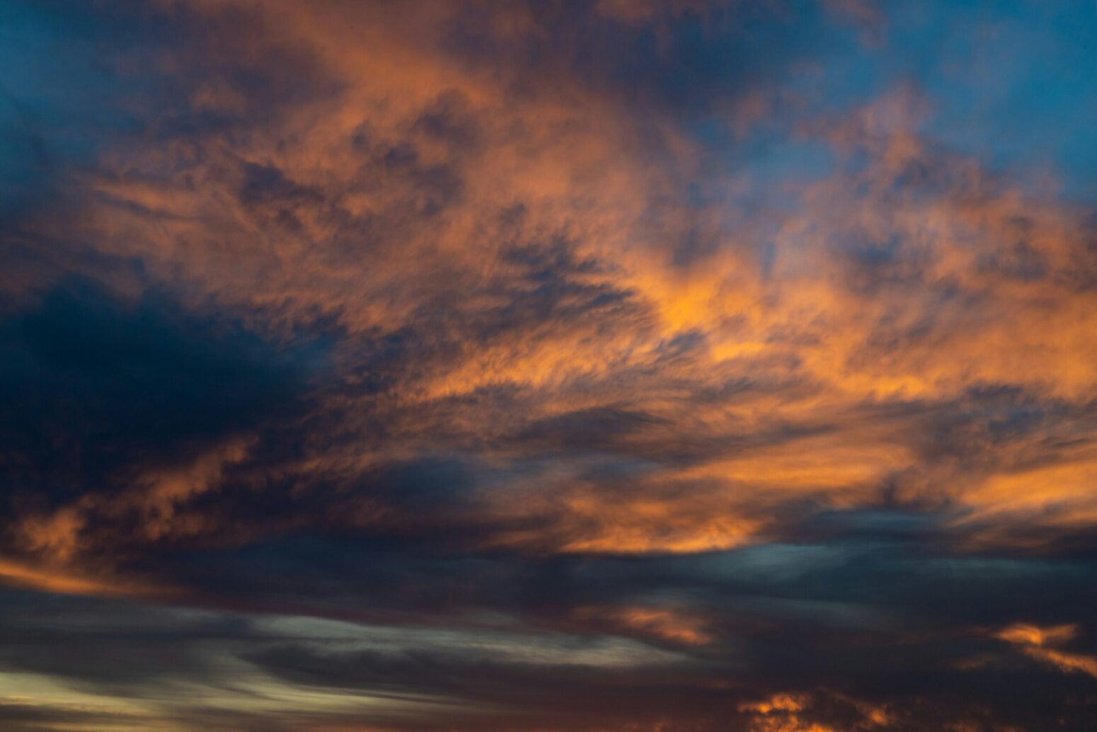 An image of a sky scattered with clouds with a blue and orange hue