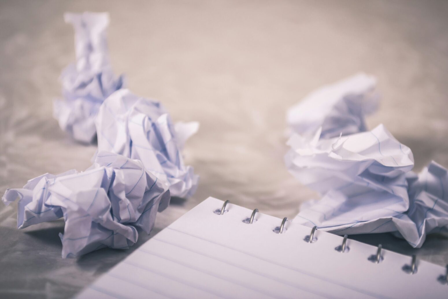 A notepad and three crumpled pieces of paper