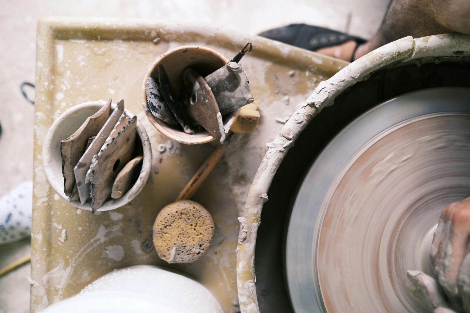 A hand working with stoneware clay on a Brent wheel.
